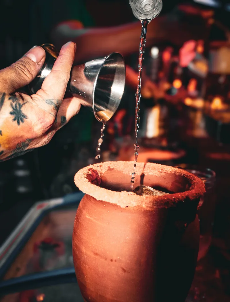 Bartender Aloha sirviendo coctel sobre cantarito con jigger